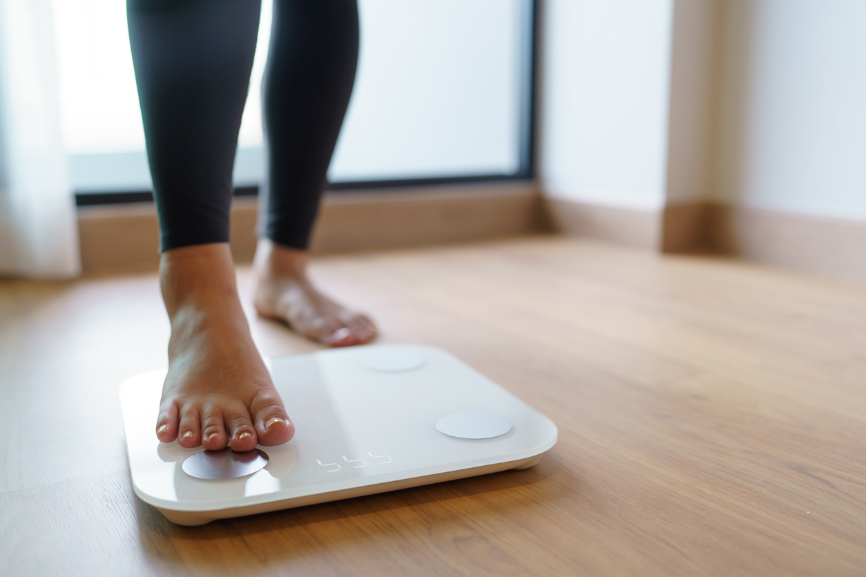A woman weighs herself on a digital scale as part of her peptide weight loss program.